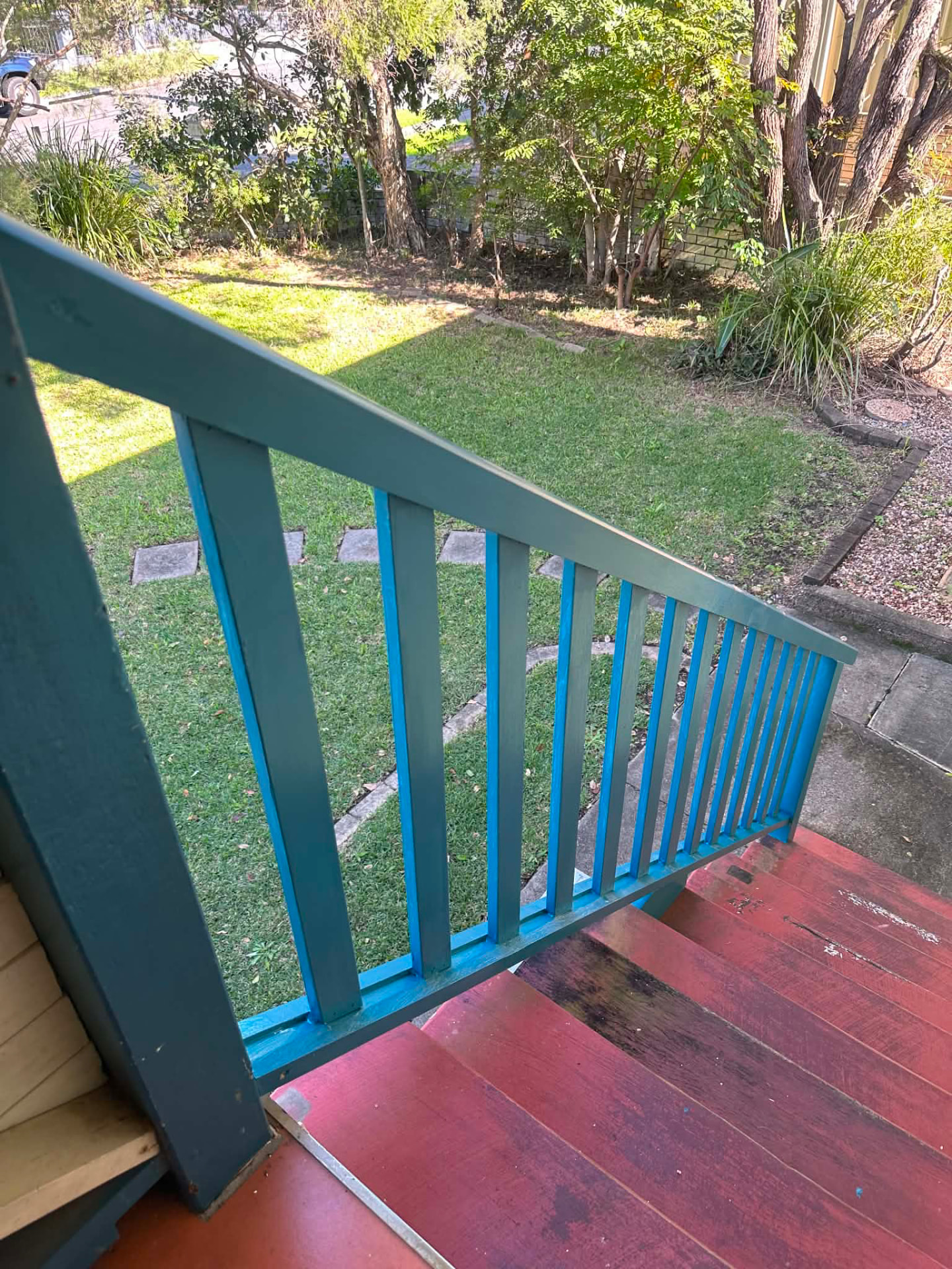 Blue and teal painted stair balustrade overlooking a mowed lawn