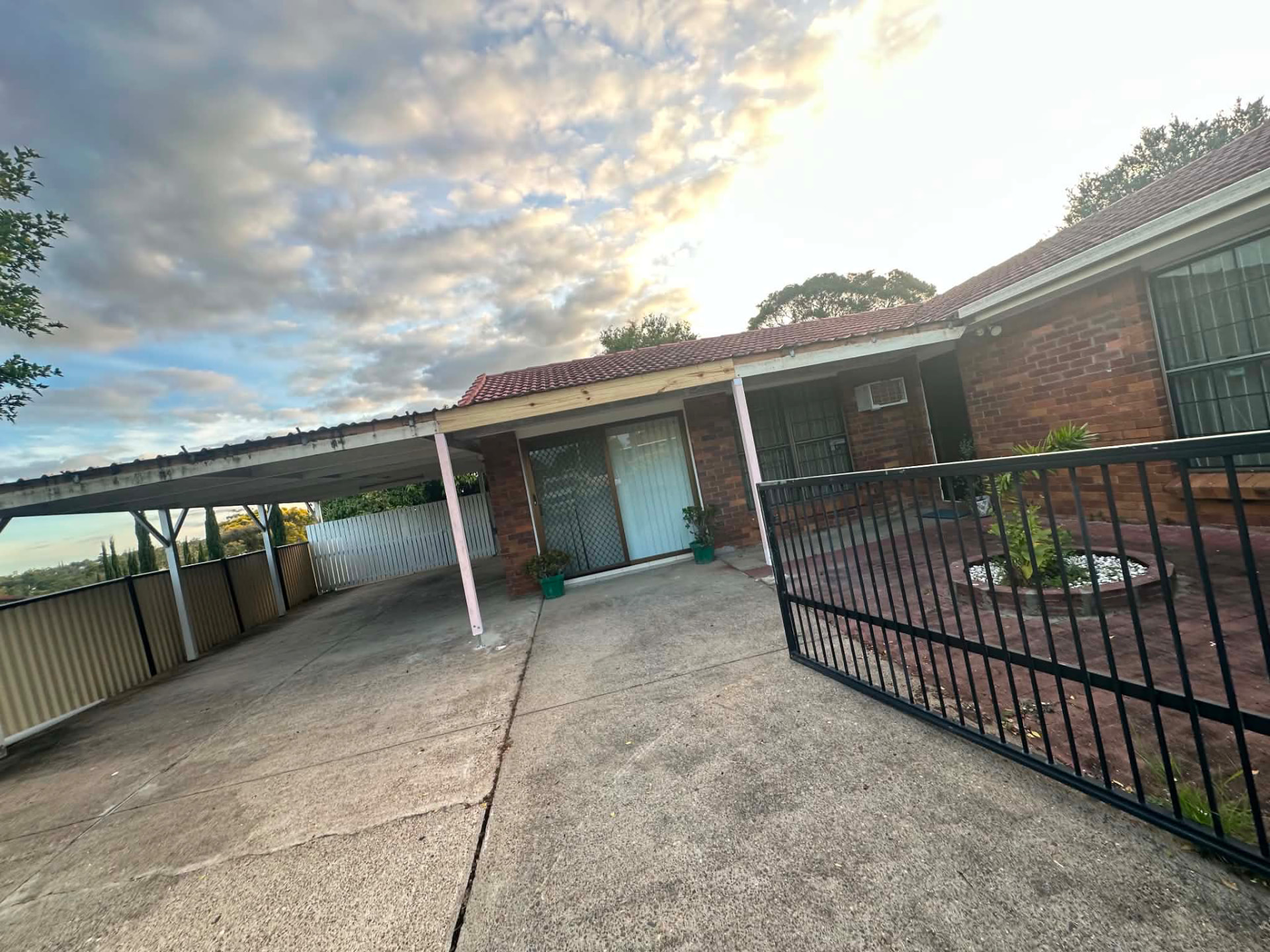 Clean carport and front entry of a brick home at sunset